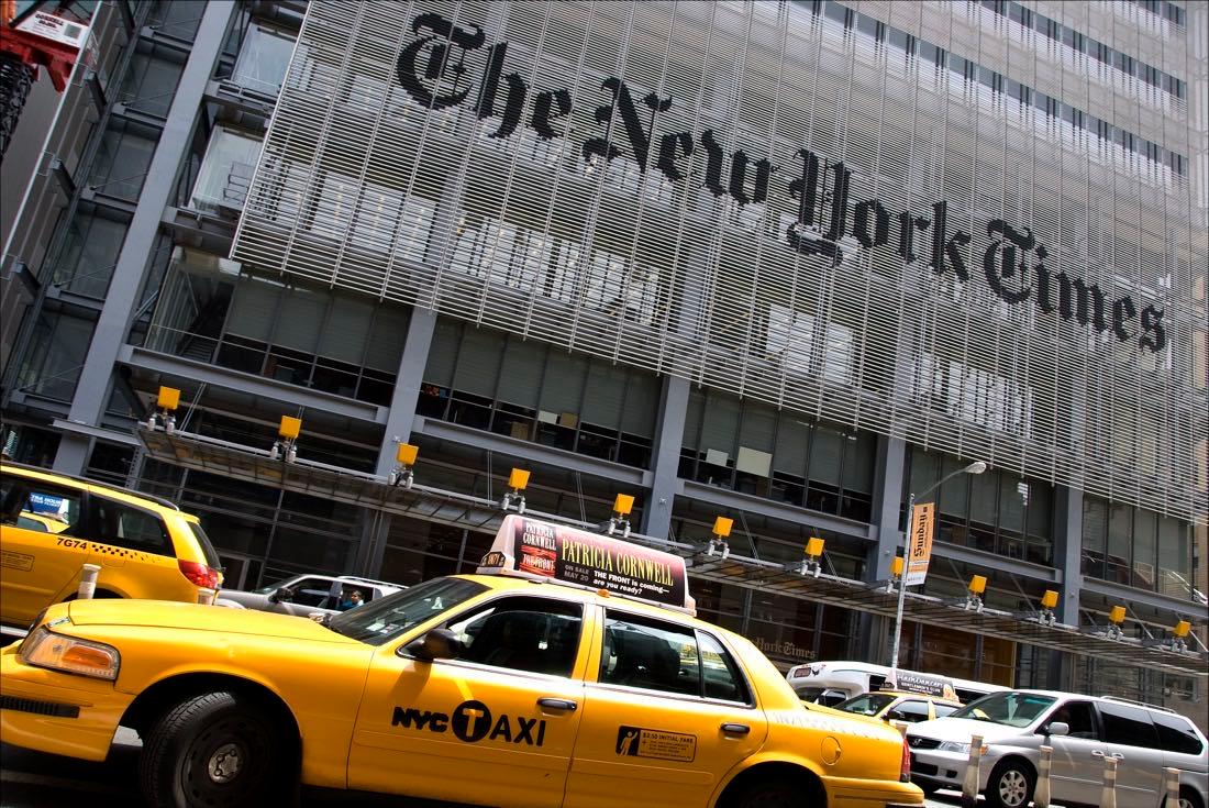 The New York Times Building on Eighth Avenue, New York, with yellow taxis passing beneath the masthead