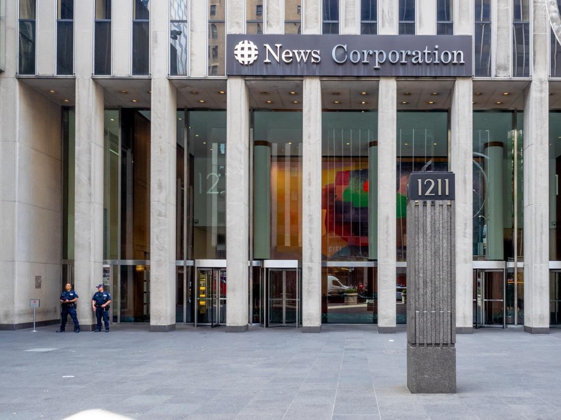 The lobby of 1211 Avenue of the Americas, New York, under the News Corporation sign, with two police officers standing by the doors