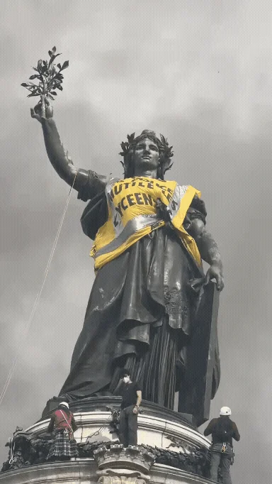 Animated image of the statue of the Republic on Place de la République in Paris, draped in a yellow banner saying the police mutilate school students, with climbers in helmets on the plinth below. Everything except the banner is in black and white.