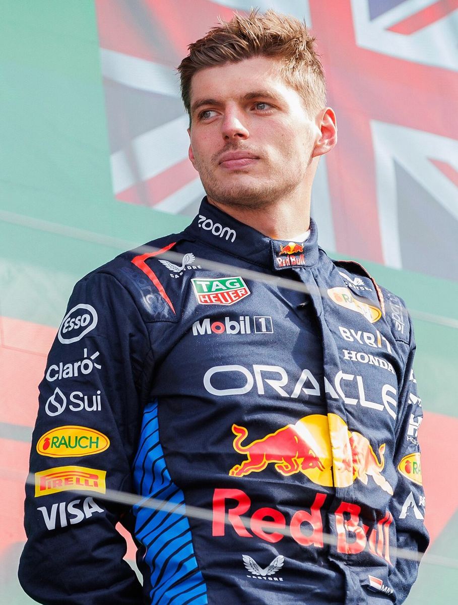 racing driver in team suit standing before a flag backdrop