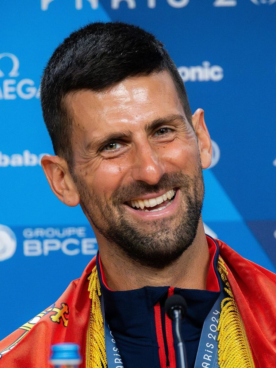 Close-up smiling man speaking at a press conference backdrop